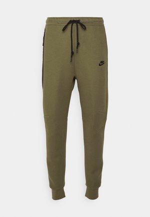 Oliven grønne Nike sweatpants med sorte sidelapper, elastisk talje og snorelukning. Har syede detaljer og logo.