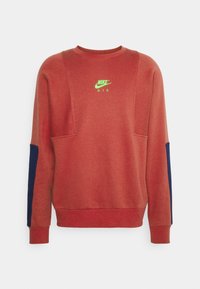 Röd sweatshirt med lång ärm, som har en rundad krage och blå detaljer på ärmarna. Visar en neongrön Nike "Air"-logotyp.