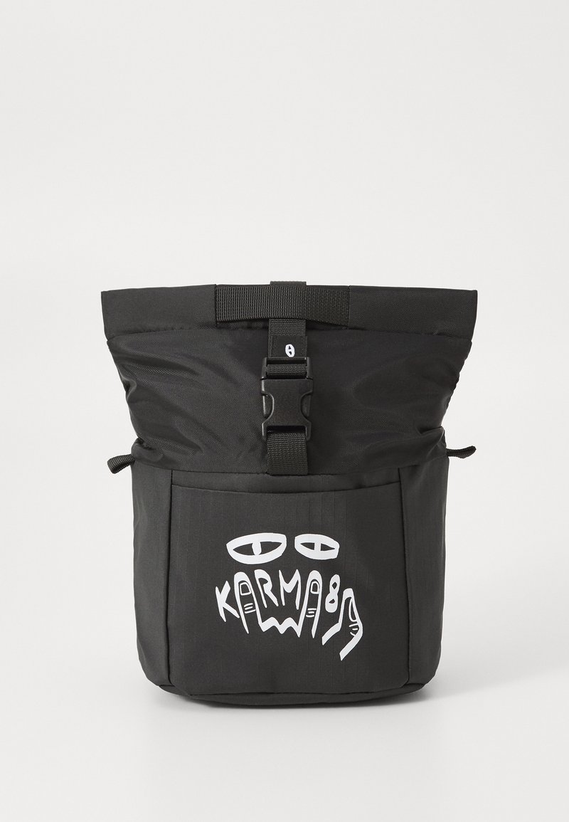 Sac à dos noir avec un dessus repliable, équipé d'une fermeture à clip. La poche frontale présente du texte graphique blanc et des motifs abstraits. Texture de tissu durable.