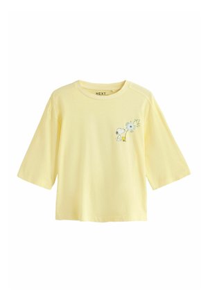 Lys gul croppet T-shirt med Snoopy og Woodstock tegneserie nær et mælkebøtteprint på venstre bryst.