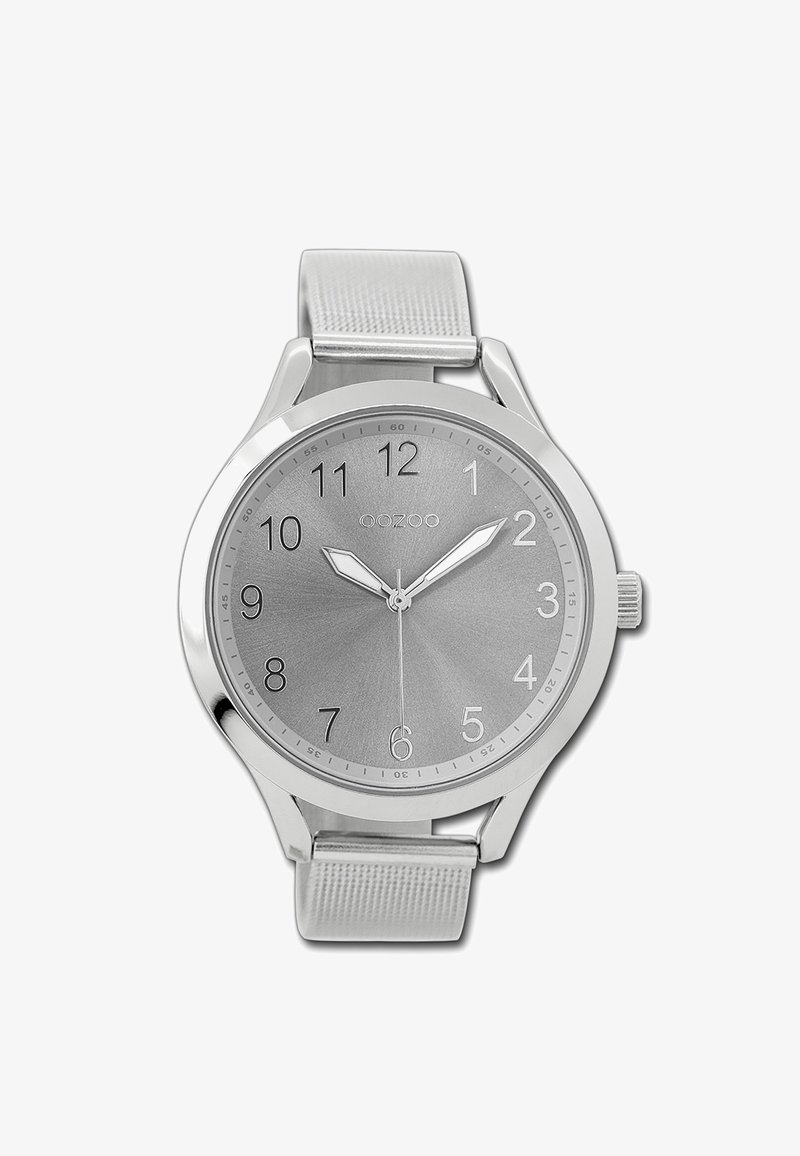 Montre argentée avec un bracelet métallique, cadran rond, fond gris, chiffres arabes et deux aiguilles argentées. Logo de la marque visible en haut.