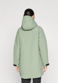 Zelený izolovaný parka s kapucňou, s jemne textúrovaným povrchom, dlhými rukávmi a akcentom z Velcro na manžetách.
