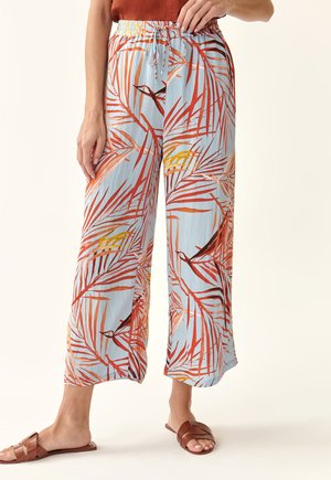 Pantalons larges bleu clair avec un motif de feuilles tropicales en rouge, orange et jaune. Taille élastique avec un détail de cordon de serrage.