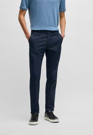 Navy blue trousers made of lightweight fabric, featuring a slim fit, side pockets, and belt loops, paired with a light blue short-sleeve shirt.