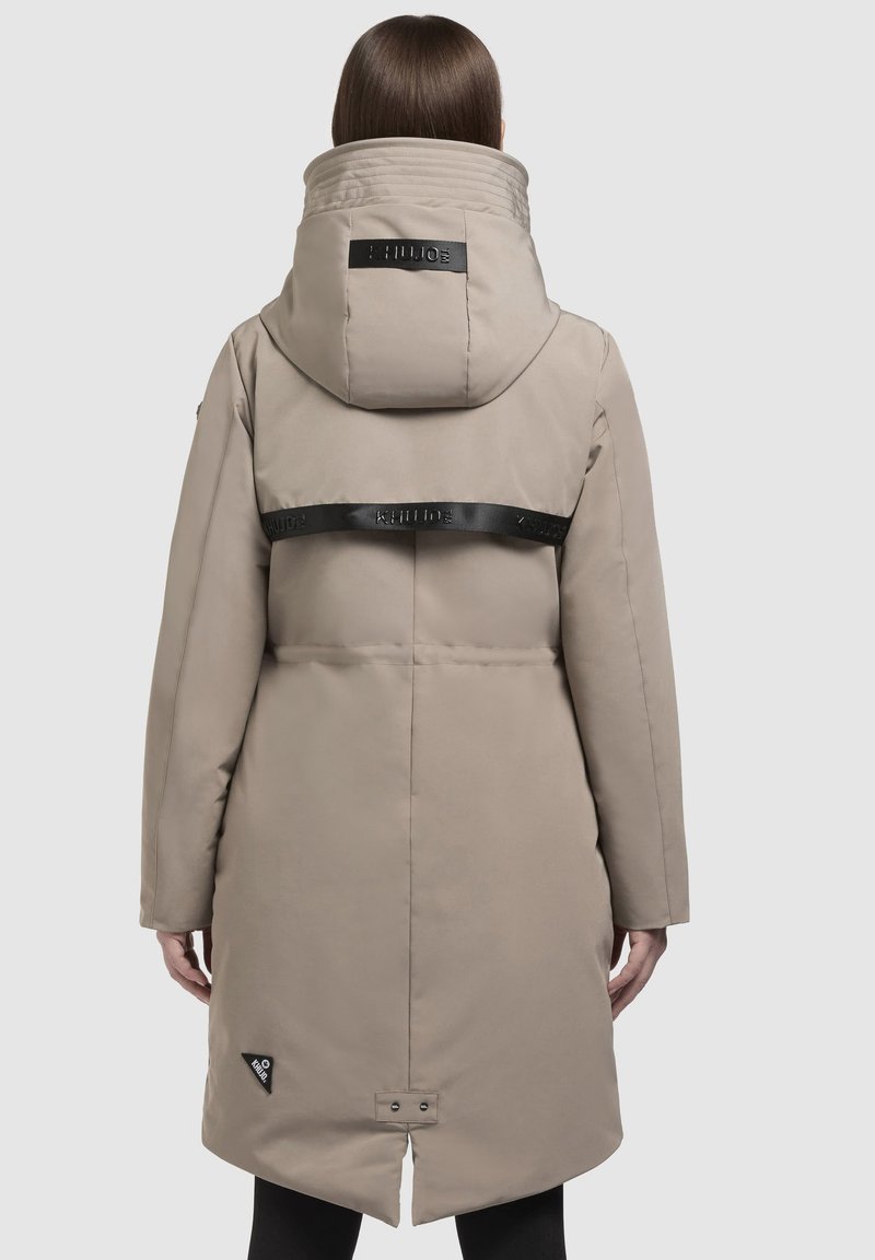 Parka imbottita beige con colletto alto, una fascia con logo nera sul retro e orlo curvato. Texture liscia e dettagli hardware minimi.
