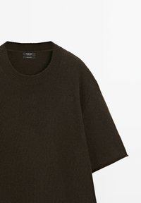 Maglione corto a maniche corte, di colore marrone scuro, con collo rotondo a costine e una texture morbida, presentato su uno sfondo bianco. Design semplice e minimal.