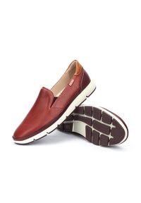 Zapatos rojos de cuero sin cordones con diseño perforado y acentos en color marrón. Suelas de goma blanca con patrones texturizados para agarre.