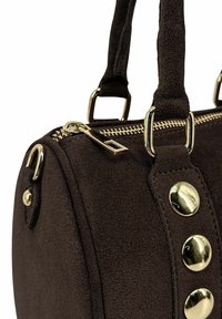 Sac en suède marron foncé avec fermeture éclair dorée, clous ronds dorés et poignées doubles attachées par des anneaux rectangulaires dorés.