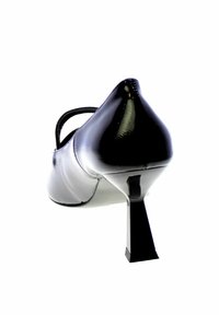 Scarpa con tacco alto bianca e nera con punta affilata, finitura in pelle lucida e tacco quadrato. Presenta una cinghia decorativa sul collo del piede.