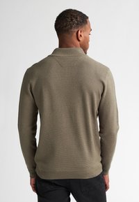 Pulover tricotat verde măsliniu cu guler polo, material texturat și manșete cu nervuri; stil ajustat și cusături plate pe spate.