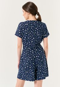 Abito blu navy con maniche corte, stampa floreale in bianco e verde, vita cintrata e vestibilità morbida, tessuto liscio, lunghezza al ginocchio.