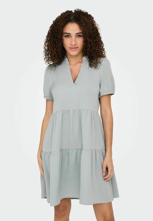 Robe courte à manches courtes, gris clair, avec un décolleté en V, un design à volants, une jupe froncée et une texture subtile. Tissu doux et fluide avec une silhouette décontractée.