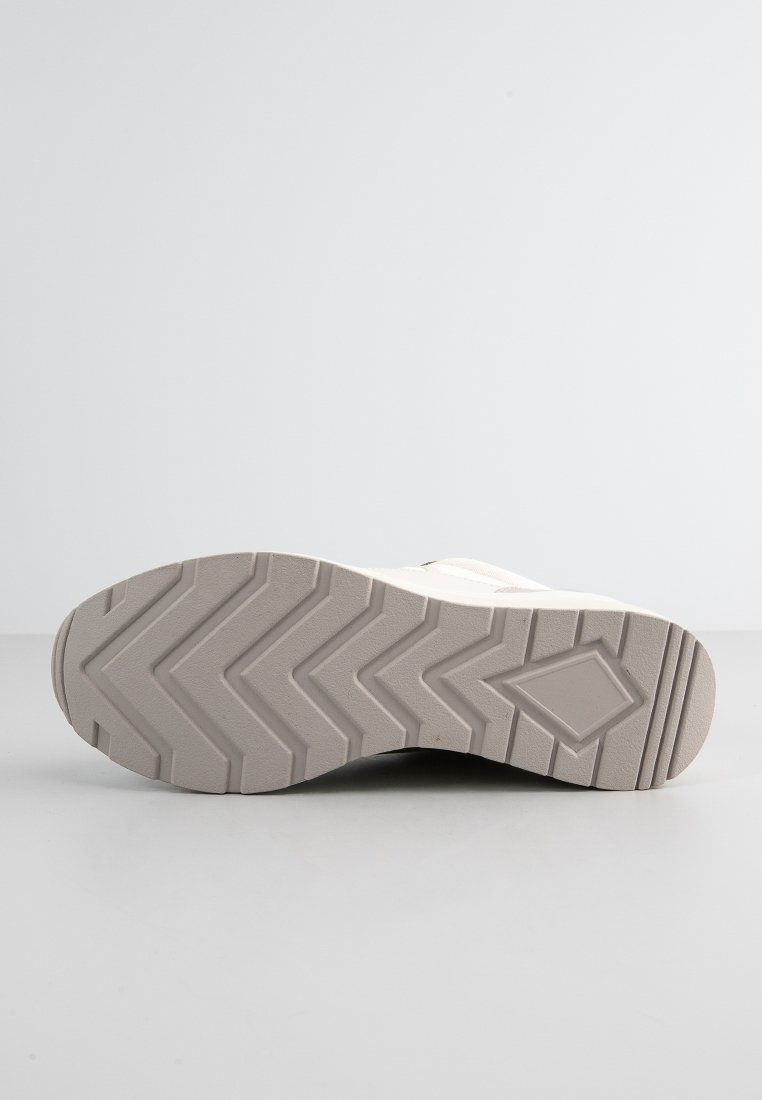 Sole di sneaker di colore chiaro con un motivo a zigzag, realizzata in gomma, caratterizzata da una base piatta e bordi leggermente rialzati.