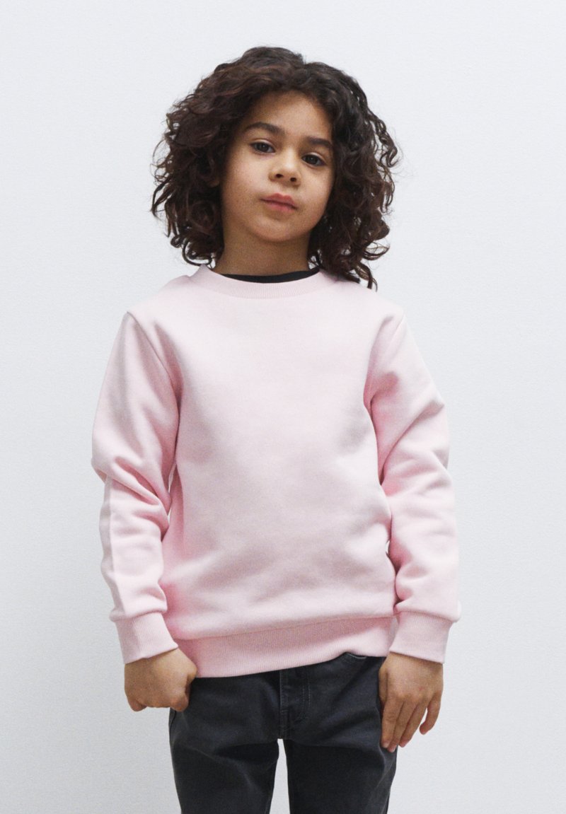 Felpa rosa chiaro con collo rotondo e polsini a costine, abbinata a pantaloni grigi scuri. Tessuto morbido, progettata per un look informale.
