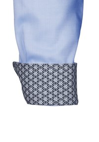 Camicia a maniche lunghe azzurra con polsini in navy a motivo, caratterizzati da disegni circolari bianchi. Il tessuto presenta una leggera texture e una finitura liscia.