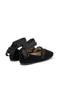 Schwarze Wildlederballerinas mit abgerundetem Zehenbereich, ausgestattet mit einem bestickten Riemen und großen Schleifenbändern an der Ferse. Strukturiert Oberfläche mit glattem Innenleben.