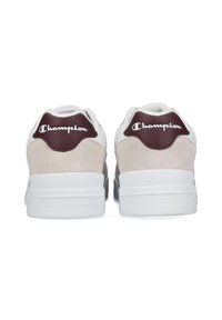 Weiße Sportschuhe mit beigen Wildlederakzenten und weinroten Fersenlaschen mit "Champion"-Logo. Strukturierte Gummisohlen für besseren Halt.