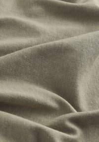 Tessuto verde oliva che presenta una superficie morbida e texturizzata con un fine motivo a maglia e un drappeggio delicato, ideale per abbigliamento o imbottiture.
