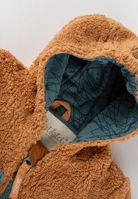 Giacca a felpa marrone con cappuccio, foderata in blu a motivo e con un'etichetta sul cursore della zip recante la scritta "SIGKID."