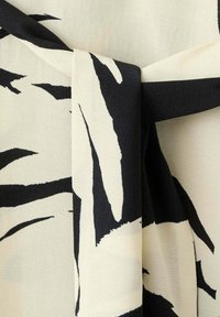 Tissu à motif abstrait noir et blanc noué en un nœud lâche avec une texture lisse et un contraste fort.
