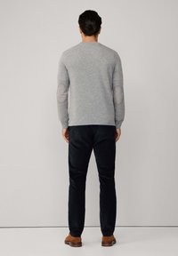 Szary sweter z dzianiny z łatkami na łokciach, okrągłym dekoltem i długimi rękawami, w połączeniu z ciemnymi spodniami i brązowymi butami. Prosty, teksturowany wzór.