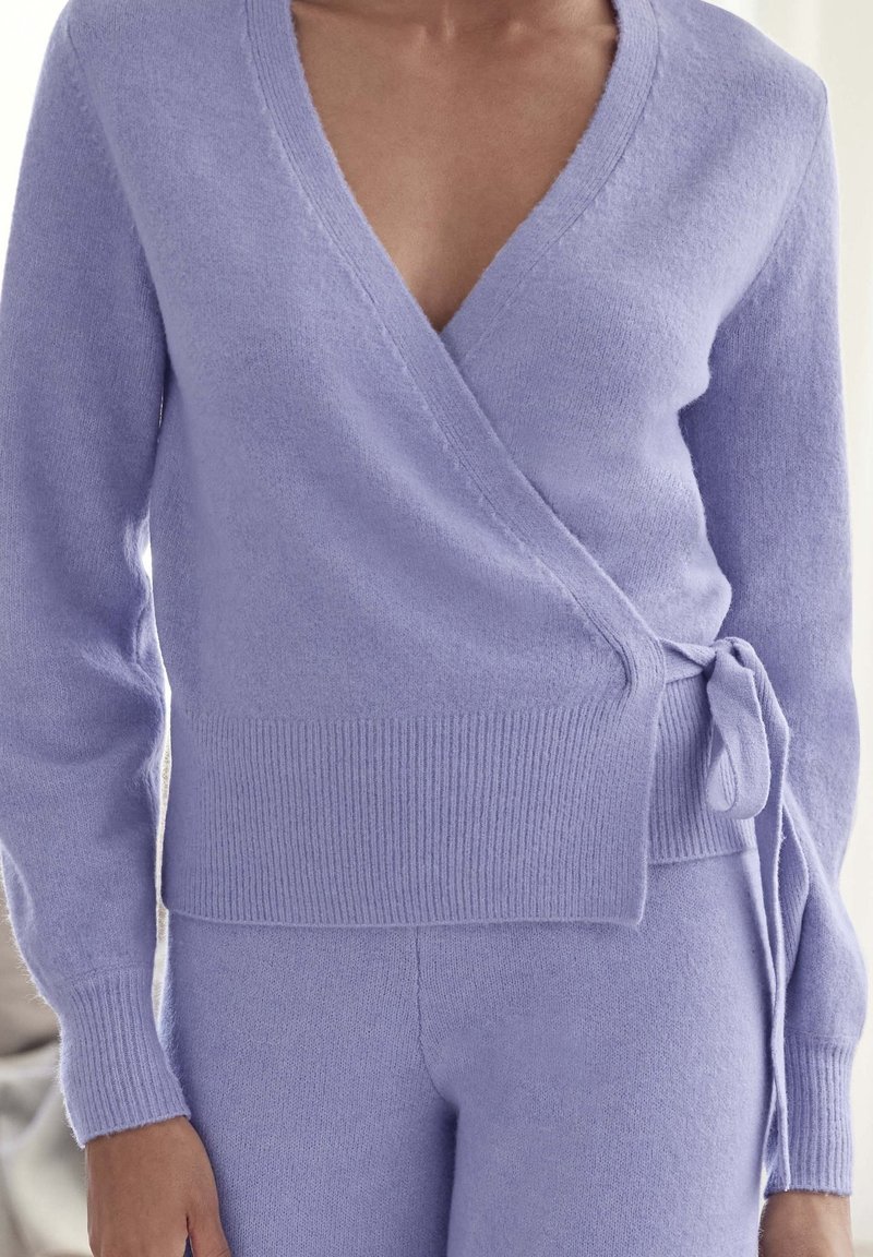 Lavendelkleurige wikkeltrui van zacht gebreid materiaal, met een diepe V-hals, lange mouwen en een gestrikt tailleband voor een getailleerde silhouette.