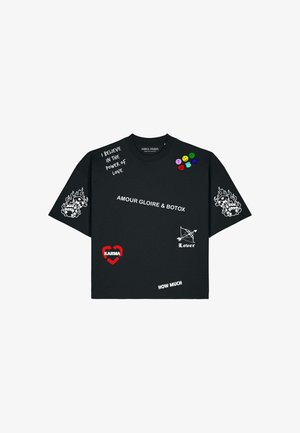 Maglietta nera con testo bianco e grafiche, comprese "AMOUR GLOIRE & BOTOX," fiamme sulle maniche, cuori e frasi come "I BELIEVE IN THE POWER OF LOVE."