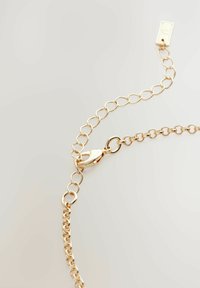 Goldene Kettenarmbänder mit ovalen Gliedern und einem Karabinerverschluss, die eine glatte, reflektierende Oberfläche und ein minimalistisches Design präsentieren.