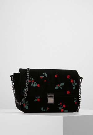 Schwarze Samt-Umhängetasche mit silberner Kette, Metallverschluss und roter Blumenstickerei mit grünen Blättern.