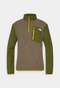 Pullover in pile di colore verde oliva e marrone, dotato di mezza zip, tasca sul petto con zip gialla e logo sulla parte superiore sinistra.