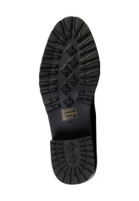Suela de zapato de goma negra con patrón de textura, que presenta un diseño central en forma de diamante y pequeñas formas parecidas a cruces. Talla marcada como 38.