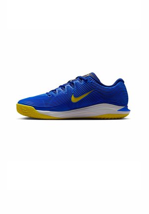 Blauwe sportschoenen met ribbeltextuur, gele accenten op de zool en swoosh, voorzien van een witte middenzool en een traditioneel vetersysteem.