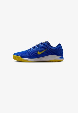 Blauwe sportschoenen met ribbeltextuur, gele accenten op de zool en swoosh, voorzien van een witte middenzool en een traditioneel vetersysteem.