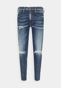 Slim-fit blå denimjeans med slitna hål på låren och knäna, med framfickor och bälteshällor.