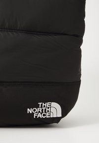 Juodas p�ūkinis krepšys su sklandžiu paviršiumi ir siuvinėtomis dalimis. Priekyje yra baltas logotipas "THE NORTH FACE", o dugnas pagamintas iš tvirto juodo audinio.