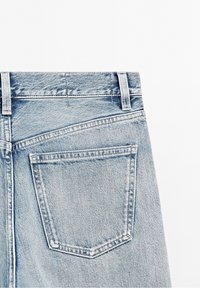 Jean en denim bleu clair montrant la poche arrière, les passants de ceinture et les coutures détaillées sur un fond blanc.