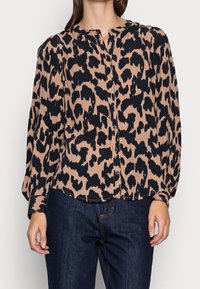 Blusa con stampa leopardata in beige e nero, dotata di chiusura a bottoni sul davanti, maniche lunghe e una vestibilità rilassata con spalle e polsini arricciati.