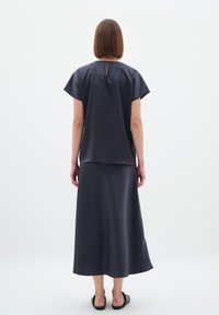 Mørkegrå, kortærmet bluse med rund halsudskæring, parret med en matchende ankel-længde nederdel. Glat tekstur, minimalistisk design.