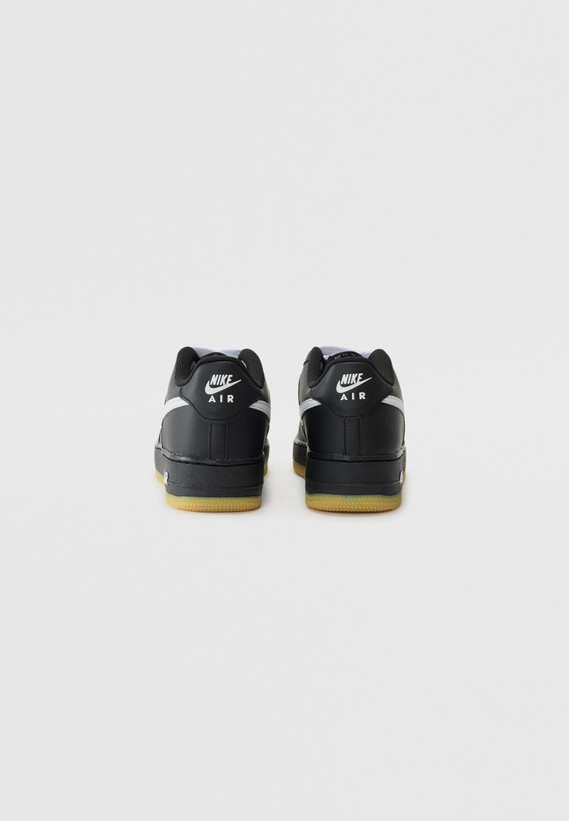 Schwarze Nike Air Sneaker mit einer glatten Lederoberfläche, weißen Akzenten und einer Gummisohle. Mit Logo an der Ferse und an den Seitenpaneelen.