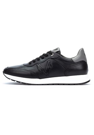 Zapatillas de cuero negro con superficie texturizada, que cuentan con una entresuela blanca, cordones negros y un acento en el talón de color gris. Logo distintivo en el lado.