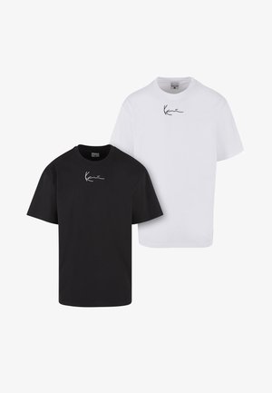 Zwei schlichte Baumwoll-T-Shirts, eines schwarz und eines weiß, jeweils mit einem kleinen, handschriftlichen Logo, das zentriert nahe dem Ausschnitt angebracht ist.