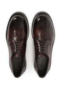 Zapatos de cuero marrón con una textura suave, punta redonda y diseño de cordones. Presentan una suela oscura y un logo sutil en la plantilla.