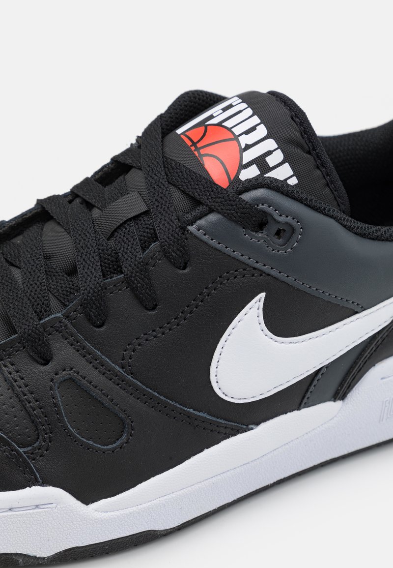 Scarpa sportiva nera realizzata in materiali sintetici, con il logo Nike bianco, lacci neri, linguetta imbottita con un logo di pallacanestro rosso e suola testurizzata.