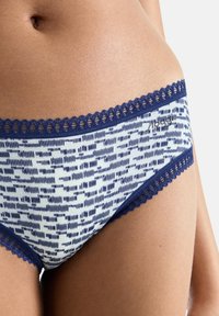 Sous-vêtements en mélange de coton avec un motif rayé vertical bleu et blanc, ornés d'une garniture en dentelle marine autour de la taille et des ouvertures de jambes.