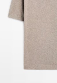 Pull en maille beige à manches courtes avec ourlet et poignets côtelés, présenté sur fond blanc.