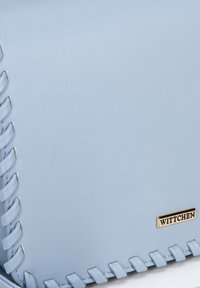 Borsa in pelle azzurro chiaro con accenti intrecciati e una placchetta logo in tonalità oro. Texture liscia con un design strutturato.
