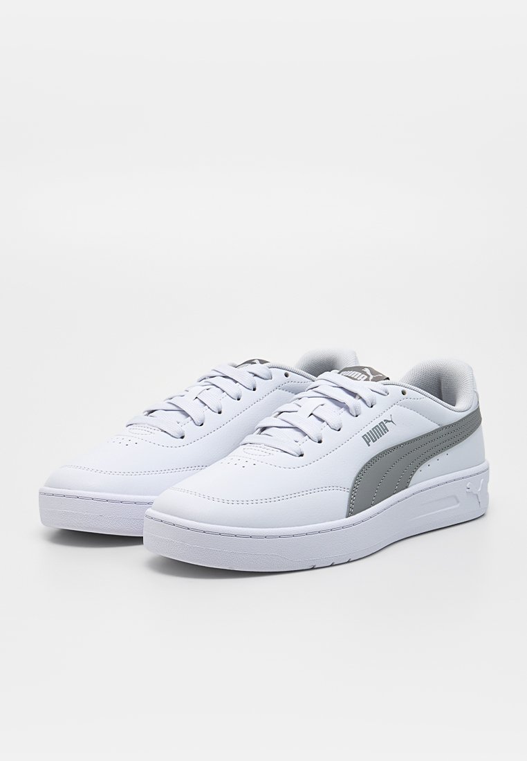 Zapatillas deportivas de piel blanca con textura lisa, con un logo PUMA gris y detalles en gris, puntera redondeada y suela plana de goma.