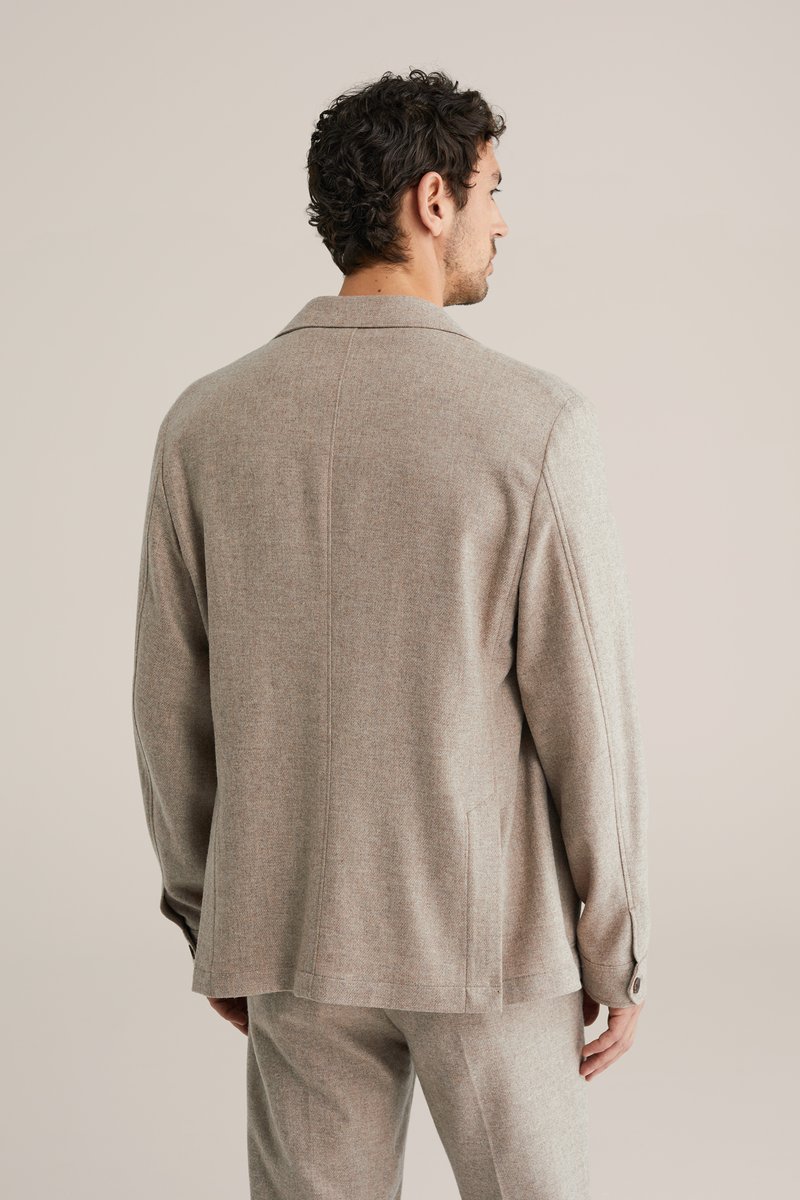 helepruun tekstuuriga jakk, millel on kohandatud lõige, tipplapid ja nupuga varrukasääred, sobitatud samas toonis pükstega. Tagantvaade toob esile õmbluste detailid.