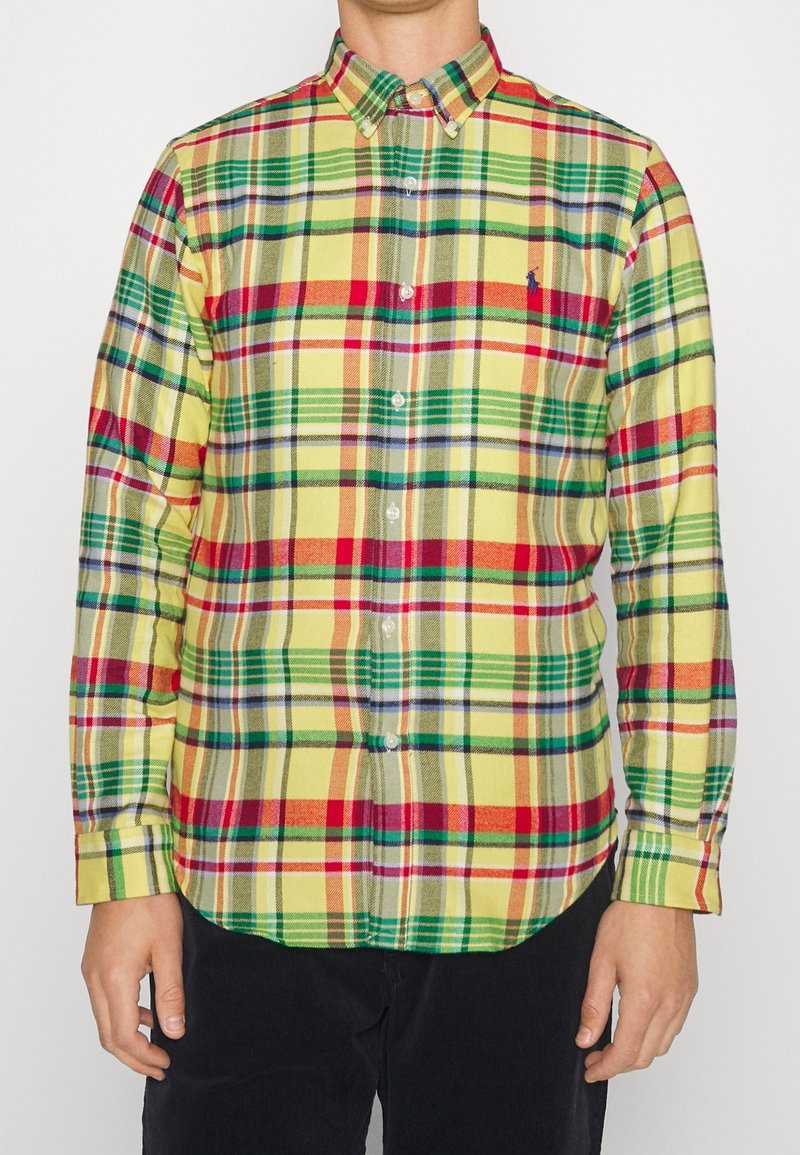 Karo košile v žluté, zelené, červené a modré barvě. Má límec na knoflíky a dlouhé rukávy s knoflíkovými manžetami. Bavlněná tkanina.