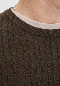 Pulover tricotat maro cu guler rotund ribatit, având un model texturat cu fir încrucișat pe întreaga țesătură și un guler interior de culoare deschisă.